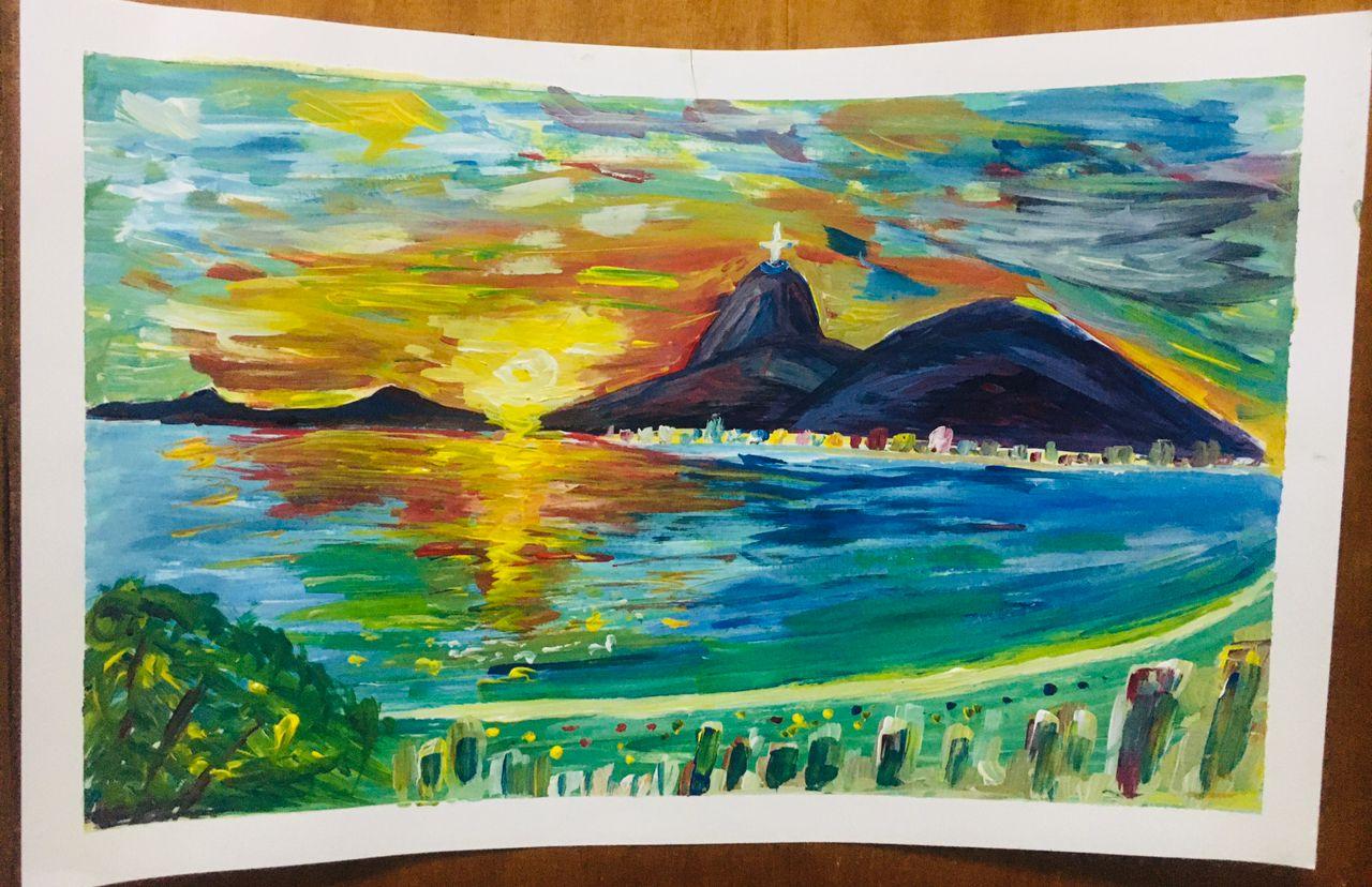 A vivid impressionist sunset over a bay with a mountain headland and a small figure of Christ the Redeemer, water blazing gold